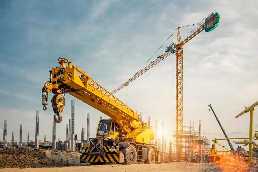 Mobile Crane on a road and tower crane in construction site. Getty Images Image used for illustrative purpose. , Getty Images